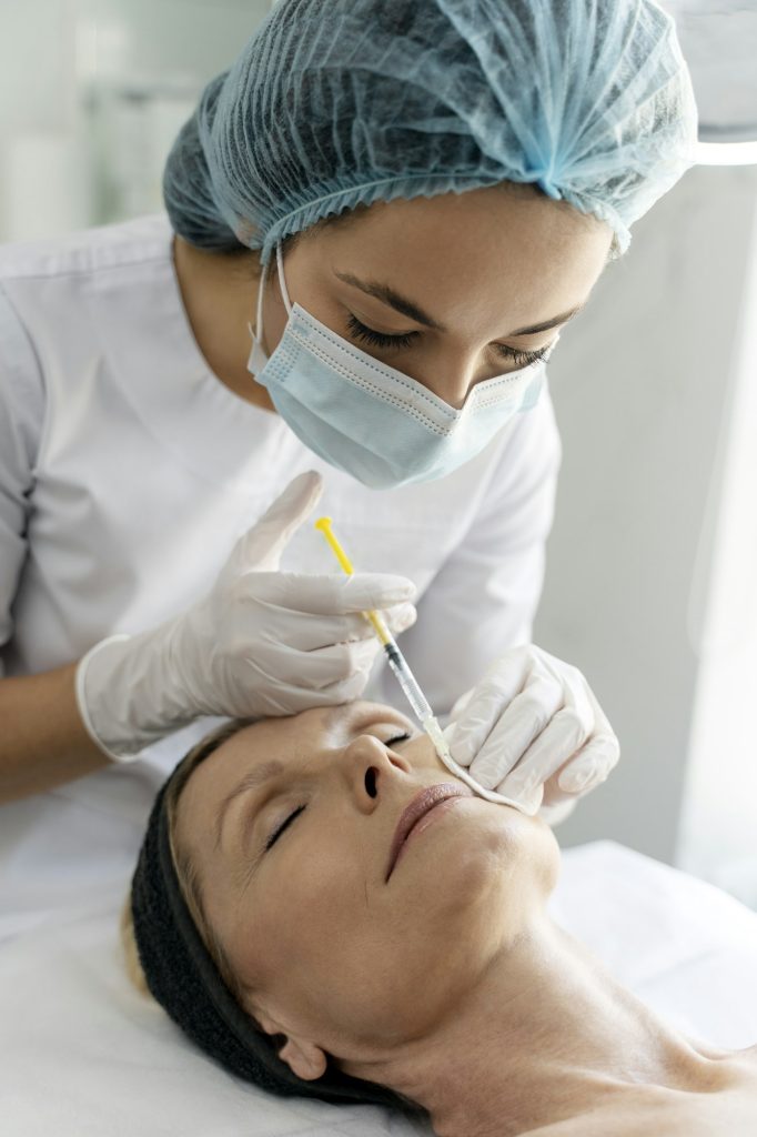 Beautician expert's hands injecting botox in senior female lips zone