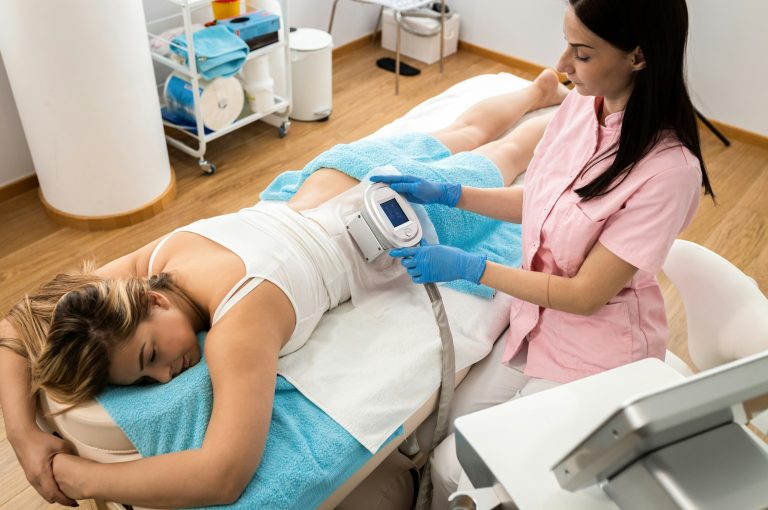Beautician therapist applying cryolipolysis treatment in beauty salon.